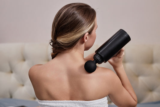 A woman relaxing on a couch using a smart handheld massager for stress relief