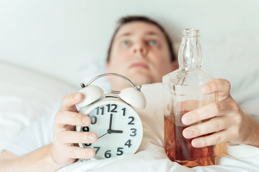 Glass of wine on a bedside table next to a clock showing late-night hours
