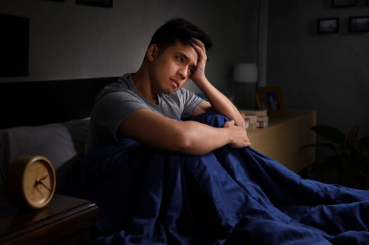 Person lying awake in bed looking stressed, symbolizing insomnia caused by anxiety.